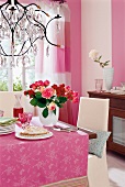 Table with rose flowers in vase with pink cloth on table with chandelier