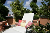 White resting sofa with cushions and side table at garden terrace at hotel in Germany