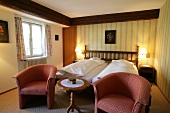 Bedroom with bed, cushion, chairs and lamp in hotel, Germany