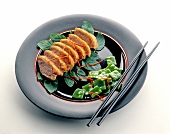 Slices of duck breast on plate with chopstick
