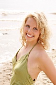 Portrait of beautiful blonde woman wearing green halter top, smiling