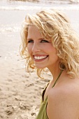 Portrait of beautiful blonde woman wearing green halter top, smiling