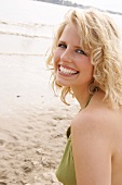 Portrait of beautiful blonde woman wearing green halter top, smiling