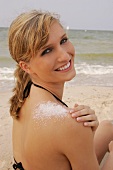 Portrait of cheerful blonde woman with salt crystals on shoulder wearing bikini, smiling