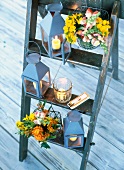 Wooden ladder with flower in hanging basket and lanterns