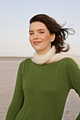 Beautiful woman wearing green sweater, jeans and scarf, standing and smiling