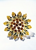 Close-up of yellow and red flower shaped brooch on white background