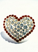 Close-up of red and white heart shaped brooch on white background