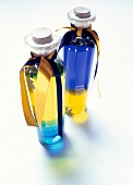Two colourful sealed oil bottles decorated with bows on white background