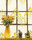 Glass beaded curtain in green with flower vase and figurines against window