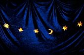 Illuminated Christmas lights in form of half moon and stars on blue background