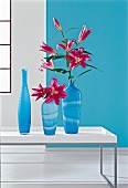 Flower vases in bottle form with single flowers in turquoise