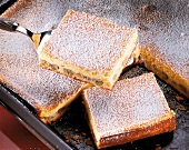 Piece of cheesecake with gooseberries and icing sugar on spatula