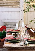 Mediterran gedeckter Tisch im Freien mit Wein & Oliven