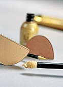 Close-up of golden cosmetic products, eyeliner, eye shadow and lip gloss 