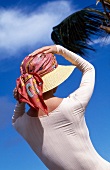Frau hält Sonnenhut fest, windig, Kopftuch um Hut gelegt, Strand