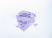 Close-up of crushed purple eye shadow on white background