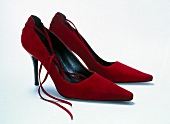 Close-up of pair of red velvet pumps on white background