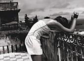 Frau in Weiß auf Terrasse, lehnt an Geländer, s/w Foto, Mini