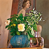 Gartenblumen in einer blauen Vase und eine Duftlampe vor einem Bild