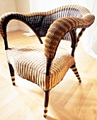 Close-up of wicker chair with armrests on wooden floor