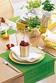 Dining table with green placemats, plates and cup full of tomatoes