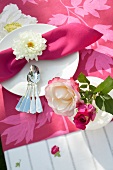 Close-up of pink napkin rolled in white blossom and roses in vase