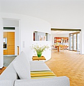 Sofa in living room with semi-circular white wall in background of dining area