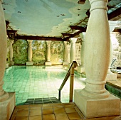 Ein Pool umgeben von Säulen und Wandmalerei.
