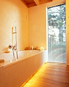 Bathroom with tiled bath tub and built-in light strip for indirect lighting