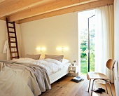 Room with sofa, chair, ladder, wooden ceiling and open patio door