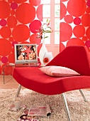 Close-up of red chair with cushion in front of red dotted curtains