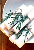 Close-up of rolled napkins with sprig of rosemary on plate