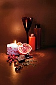 Chocolate, lit scented candle, cocoa oil and half a pomegranate on floor