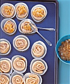 Mandel-Zimtrollen auf Backblech werden mit Topping versehen, Step 4