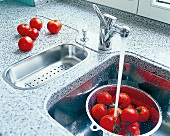 Tomaten werden gewaschen in Spüle unter fließendem Wasser