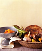 Close-up of roasted lamb leg with garlic and bay leaf on wooden plate