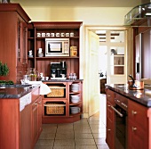 Red and brown wooden furnitures with utensils in modular kitchen