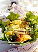 Bowl of green salad with potatoes, cheese, cucumbers, carrots and lettuce