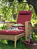 Wicker chair with red cushions under a shady tree