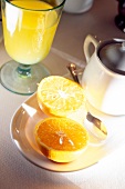 Close up of halved oranges on plate with glass of orange juice