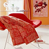 Close-up of chair with red plaid in oriental patterned blanket