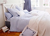 Bed with blue and white cushions, pillows and bed sheet