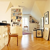 View of living room with framed pictures on wall, chair and parquet flooring