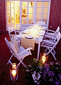 Laid out dining table decorated with candles on terrace at dusk, elevated view