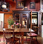Wooden dining table and chairs in front of antique cabinet with glass doors