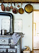 Row of pans hung above antique wood-burning cooker in country-house kitchen