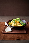 Couscous - Salat in einer braunen Schale neben einem Holzlöffel