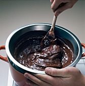 Melted chocolate being mixed with ladle in bowl