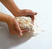 Hand kneading pasta dough on white background